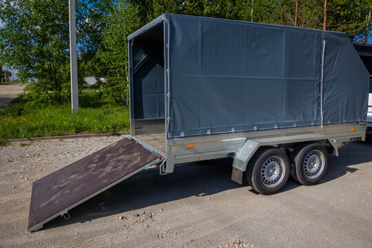 Enclosed cargo trailer with loading ramp parked outdoors, sunny roadside location. Concept: moving logistics