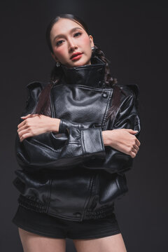 Side profile of Asian woman looking over shoulder in leather jacket for high fashion cosmetics marketing campaign luxury streetwear aesthetic urban lifestyle edgy portrait studio