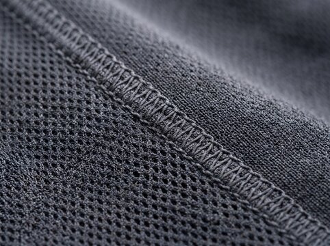 Dark gray breathable mesh fabric, macro detail of athletic textile texture, professional overlock stitching on sportswear garment