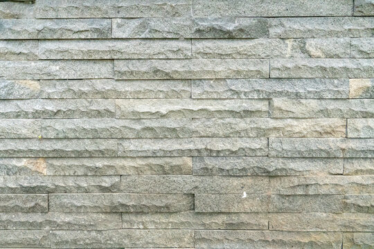 Natural stone walls with a rough, chiseled texture. Linear natural stone or granite tiles arranged horizontally.