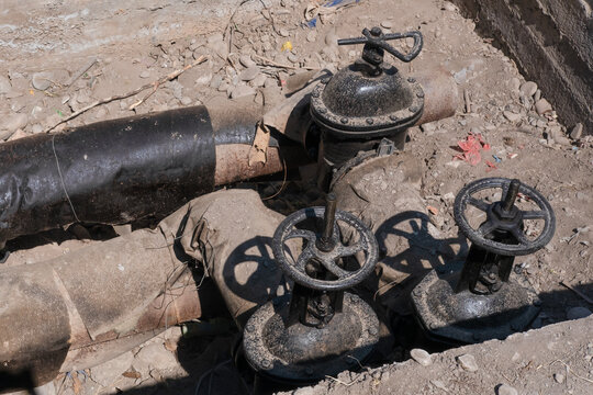Old underground water pipeline with metal gate valves exposed during excavation and maintenance work