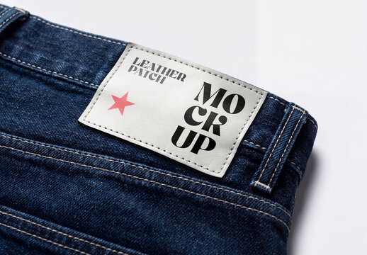 Close-up shot of a white leather patch mockup stitched onto the waistband of blue denim jeans pants