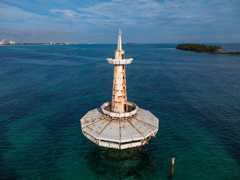 Aerial view of the abandoned white observation tower standing in the turquoise ocean waters near the coast of Nassau, New Providence, The Bahamas.