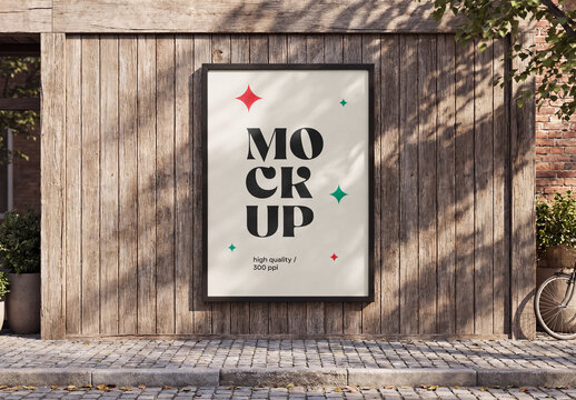 Front view of a vertical large outdoor poster billboard mockup with black frame mounted on a weathered wooden wall with tree shadows