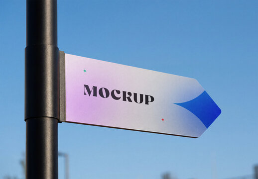 Close-up shot of an arrow-shaped street sign mockup mounted on a black metal pole against a clear blue sky background