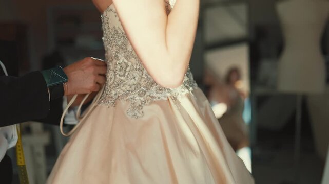 Seamstress helping bride try on wedding dress