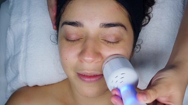Woman receiving facial cleansing high-frequency treatment