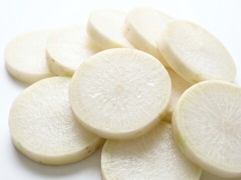 Freshly sliced white daikon radish rounds arranged on a clean white surface