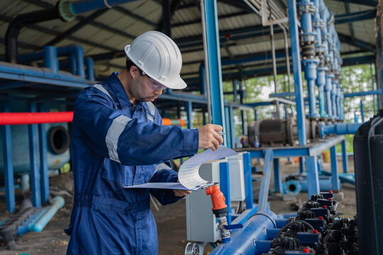 Professional engineer performing maintenance inspection of industrial water filtration system with multiple membrane units. Technician recording operational data for water treatment facility process.