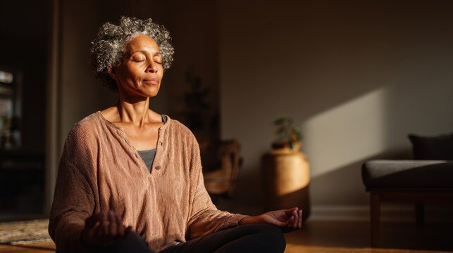 Close-up portrait of an elderly African woman practicing pranayama at home on a black yoga mat