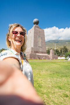 Woman smiling, taking a self portrait at the mitad del mundo equatorial line landmark