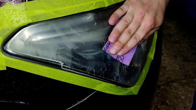 A close-up shot of washing a car headlight after sanding