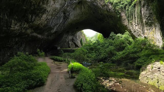 Low Drone Flight Along Walkway Toward Devetashka Cave Entrance