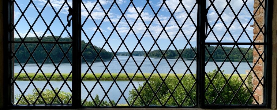 Diamond lattice window frames a serene lake view with green treelined shores