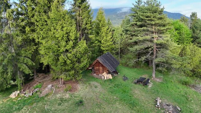 Aerial Drone Spiral Helix Shot Rising Above Rustic Forest Shelter with Fireplace in Spring Mountain Forest