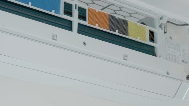 Open wall mounted air conditioner with colored filters and the inside of the unit. Concept of AC cleaning, filter change and cooling system maintenance.
