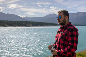 Fototapeta premium Man traveler with sunglasses looking at Canada mountain lake