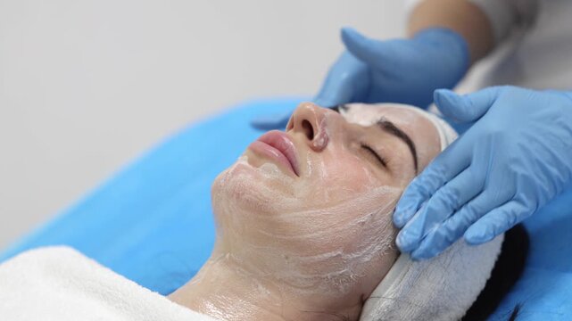 Female cosmetologist providing professional facial cleansing service in spa salon. Concept skin care, hygiene and cosmetic procedure.
