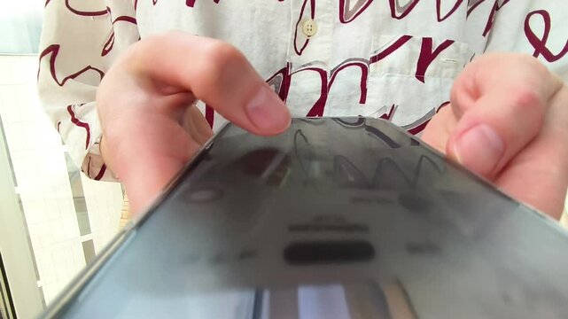 Hands holding a smartphone in close up. The phone is tapped and scrolled while screen content shifts through the clip. Mobile browsing, app use, and online communication concept..