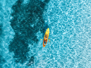 Aerial drone view of a kayakers paddling through vibrant turquoise water in deep blue sea in summer. Mallorca, Spain. Balearic Islands. Tropical paradise. Top down view of canoe. Outdoor adventure © den-belitsky