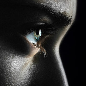 Closeup profile view of woman's eye looking into darkness