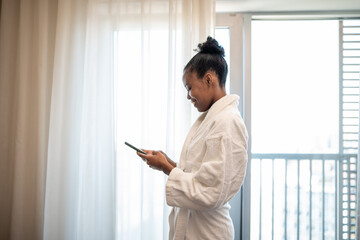 Fototapeta premium Woman in bathrobe using smartphone during morning relaxation