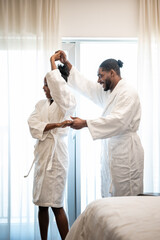 Obraz premium Happy couple dancing in bathrobes during staycation