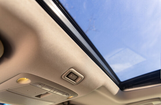 Panoramic sun roof at the car and blue sky. Clean sunroof and view at the sky from the inside or car interior