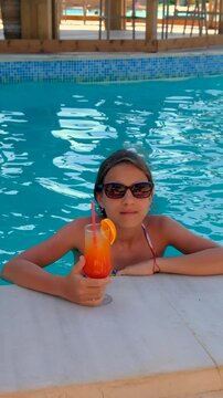 Woman in the pool with a cocktail. Selective focus. Girl.