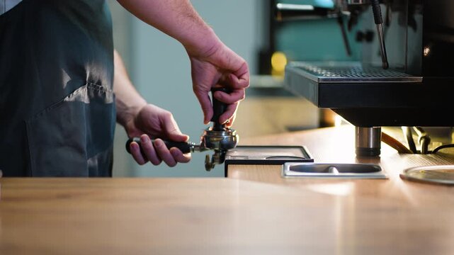 Barista tamping fresh ground coffee beans in portafilter at a cafe