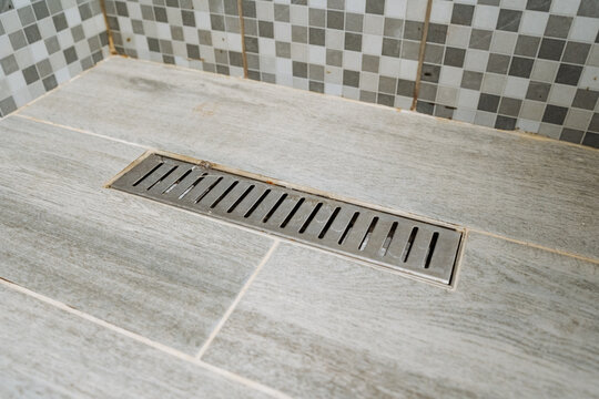 Stainless linear drain set in tiled shower floor