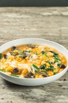 Century Egg and Pork Congee: A savory bowl of congee with preserved century eggs, lean pork, and fresh green vegetables, offering a comforting and flavorful culinary experience.