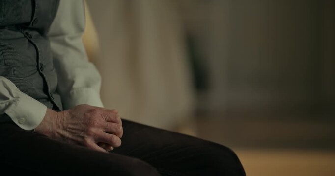 Seated adult with clasped hands in warm indoor light