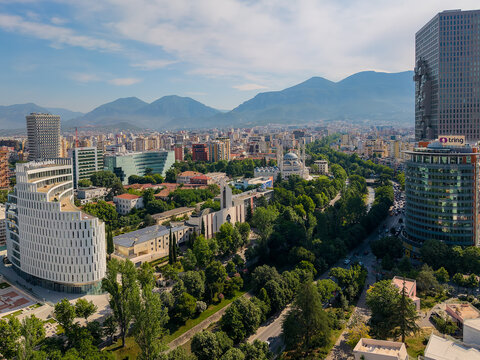 Tirane, Albania - 30 May 2026: Aerial view of the city center skyline featuring modern architecture, the Namazgah Mosque, and lush green parks against the Dajti mountain range.