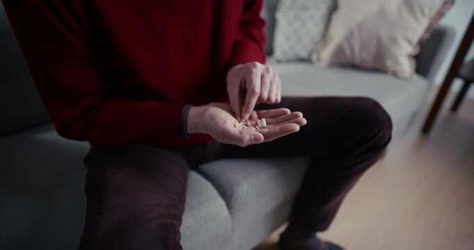 Person holding pills in open hand while another hand reaches in a living room