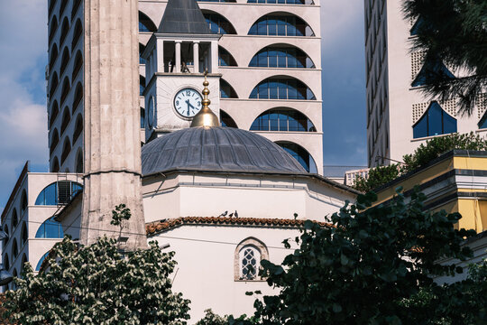 View of the Et'hem Bey Mosque and the Clock Tower with modern buildings and green trees in the background Tirane, Tirana County, Albania.