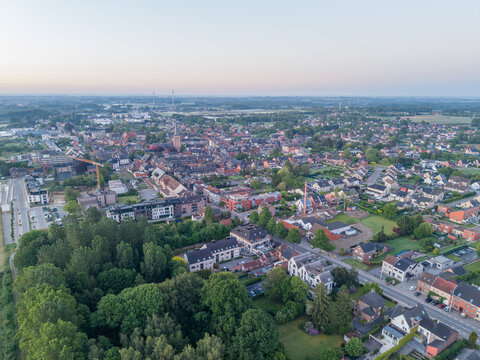 Diepenbeek, Belgium. Aerial drone view of small European town center with residential neighborhoods and urban expansion at sunrise