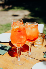 Fototapeta premium Three orange drinks with ice on a wooden table outdoors