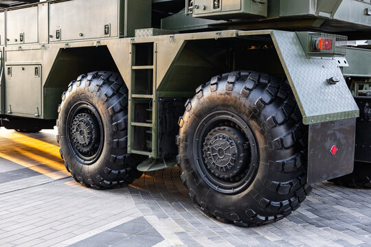 Military equipment and army equipment.. Display of military wheels under city illumination. Exhibition of heavy military wheels highlighting tread pattern hub structures and suspension