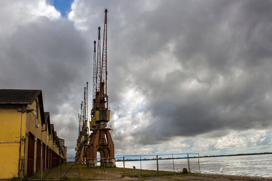 Historic cranes and yellow warehouses at Cais Mau&aacute; (Mau&aacute; Wharf) under a cloudy sky in Porto Alegre, Rio Grande do Sul, Brazil. 