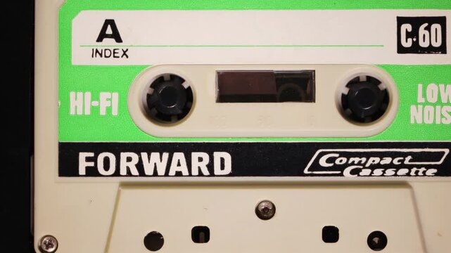 Generic green vintage audio cassette tape playing back on side A with camera panning to the right showing C60 and low noise labels