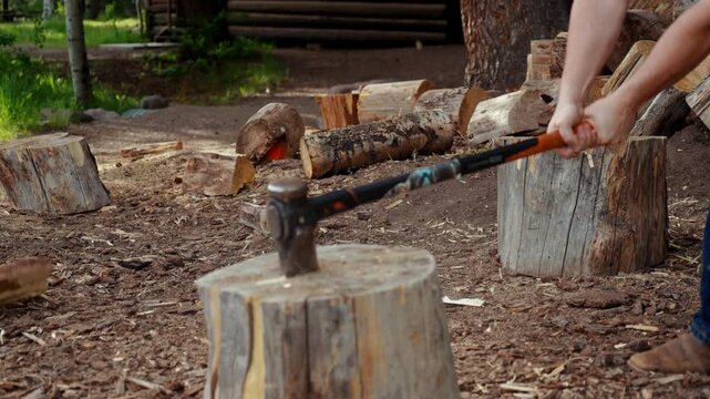 Man splitting logs of firewood with large axe in Colorado