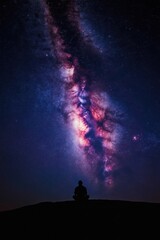 Fototapeta premium Man sits in meditation silhouette under bright Milky Way galaxy. Contemplating cosmos, universe, night sky, celestial wonders, inner peace, spiritual connection, solitude. Serenity under stars.