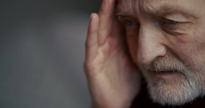 Thoughtful older man in profile with serious expression and soft indoor light