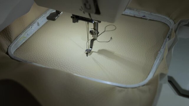 Machine embroidery of circles with black thread on light brown leather fabric.