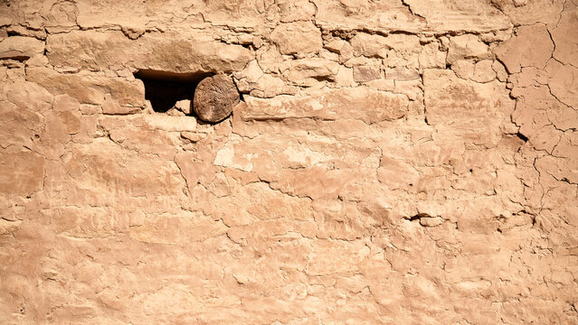 Texture, ancient Anasazi adobe plaster and sandstone wall at Cliff Palace, Mesa Verde, cracking, with visible interior wood pole reinforcement in upper left