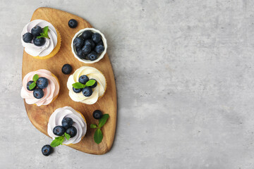 Obraz premium Yummy cupcakes with blueberries and mint on grey table, top view. Space for text