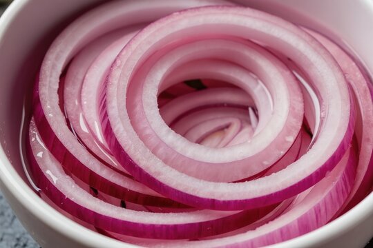 Sliced red onion rings in pickling liquid inside white bowl. Vivid purple and white layers of vegetable condiment for healthy diet and vegan food.