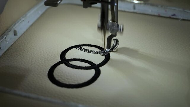 Machine embroidery of circles with black thread on light brown leather fabric.
