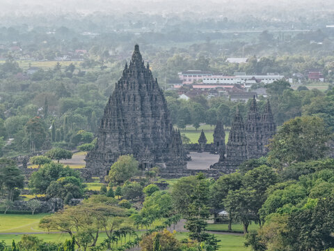 Aerial view of the historic Prambanan Temple complex with its towering stone spires surrounded by lush green trees in Prambanan, Daerah Istimewa Yogyakarta, Indonesia.